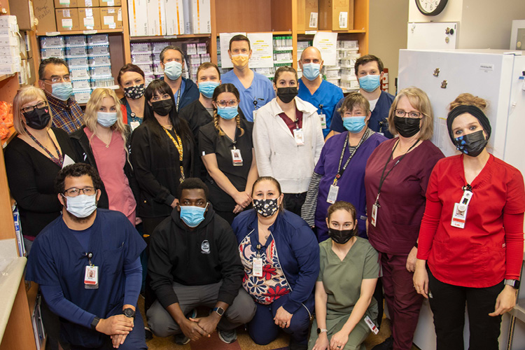 Lab employees stand together in the laboratory wearing surgical masks